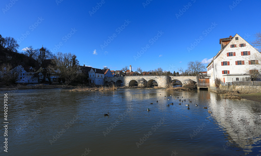 Blick über die historische Steinbrücke über den Fluss Wörnitz in Harburg in Schwaben, bei strahlend blauem Himmel im Winter. Bayern, Deutschland, 