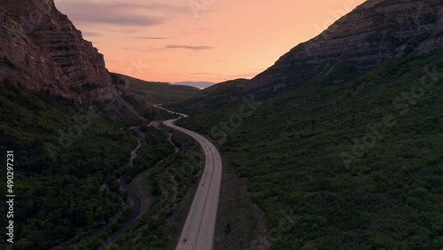 Flying through canyon with road winding through the landscape at sunset in Utah through Provo Canyon.