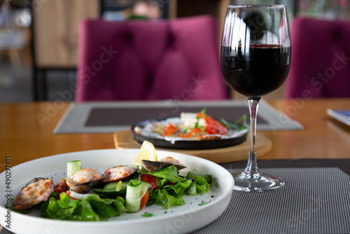 Gourmet cuisine in the seafood restaurant: mussels and a glass of red wine on a wooden table.