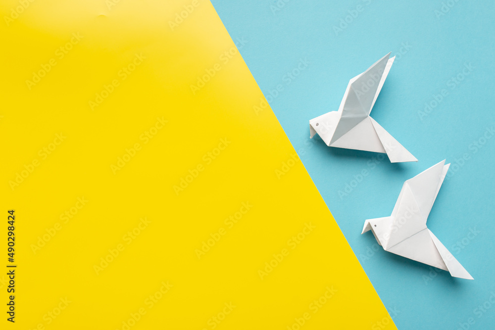 Two white birds as a symbol of peace on on blue and yellow pastel paper color for background Two white birds as a symbol of peace on on blue and yellow pastel paper color for background