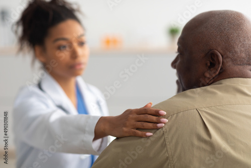 Close up of black female doctor tapping patting patient's shoulder