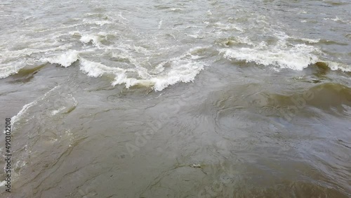 Downstream of natural river water gushing under the bridge in a close-up view. photo