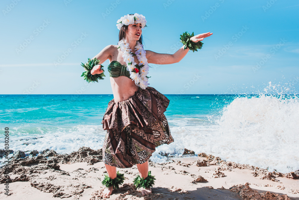 Hawaiian woman enjoys hula dancing on the beach barefoot wearing  traditional costume. Hawaii dancer. Lady dancing to the rhythm with the  waves of the sea. Woman and flowers hawai concept foto de