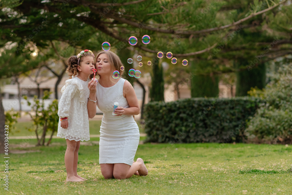 Fototapeta premium Mother and daughter blow soap bubbles outdoors.