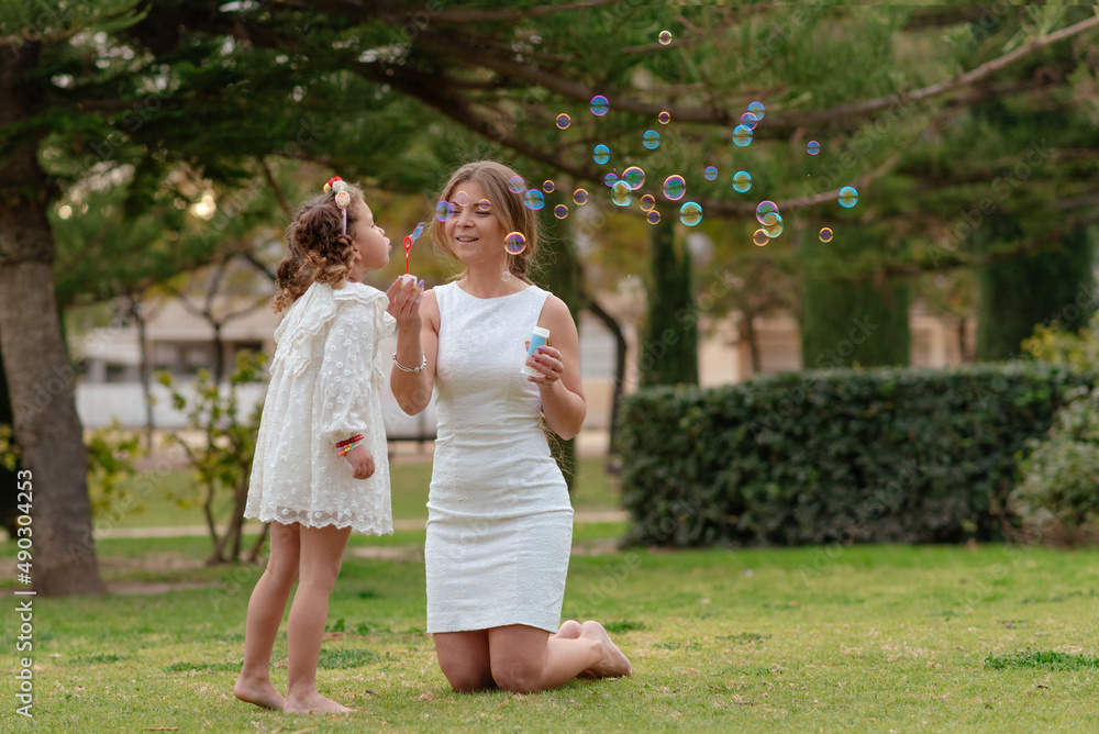Mother and daughter blow soap bubbles outdoors. Mother and daughter blow soap bubbles outdoors.