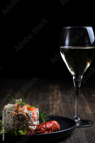 Olivier salad with red caviar served with boiled crayfish and wine