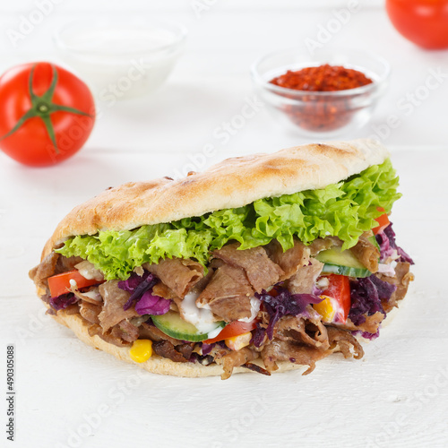 Döner Kebab Doner Kebap fast food in flatbread on a wooden board square