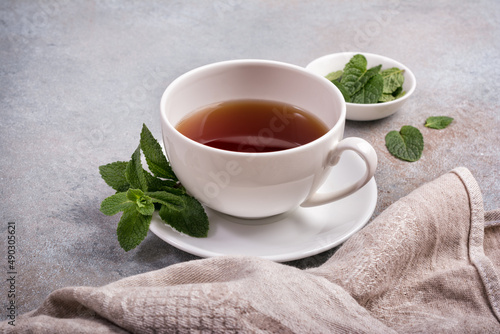 Cup with tea and green fresh mint leaves