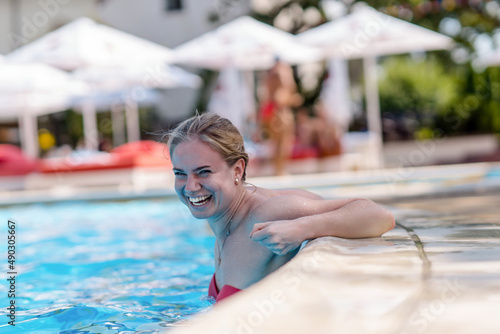 Portrait of a young smiling woman in the swimming pool.Pretty girl resting on the edge of a swimming pool.Sexy girl relaxing in water on hot sunny day.