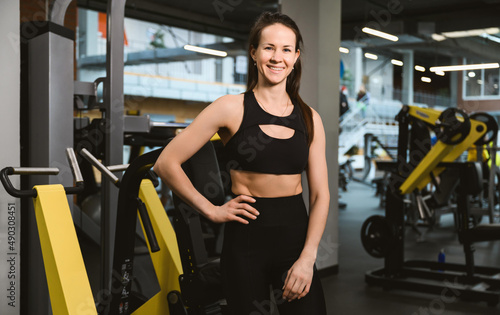 Portrait of young caucasian woman wearing sportswear bra and pants in fitness gym, sports and healthcare concept