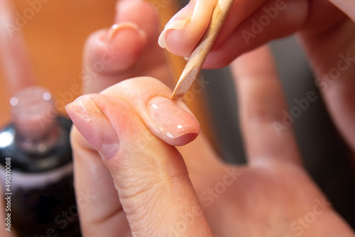 Correction of the gel near the cuticle with stick. The process of self-manicure. Image for beauty websites. Selective focus.