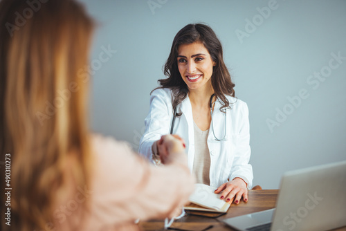 Smiling young Caucasian female doctor shake hand greeting get acquainted with female patient in hospital, happy woman physician handshake woman client make agreement sign health insurance in clinic
