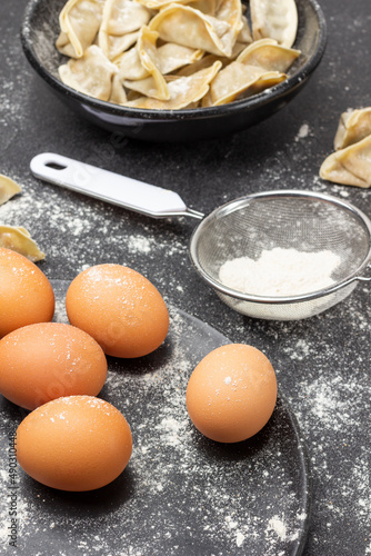 Eggs on a plate and flour in sieve.