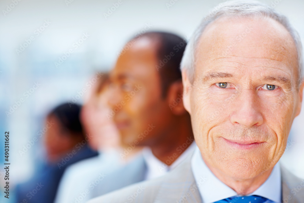 Serious senior executive with team behind him. Closeup of senior Business man with team behind him. Serious senior executive with team behind him. Closeup of senior Business man with team behind him.