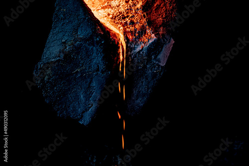 Molten and red-hot metal flows out of the ladle. soft focus