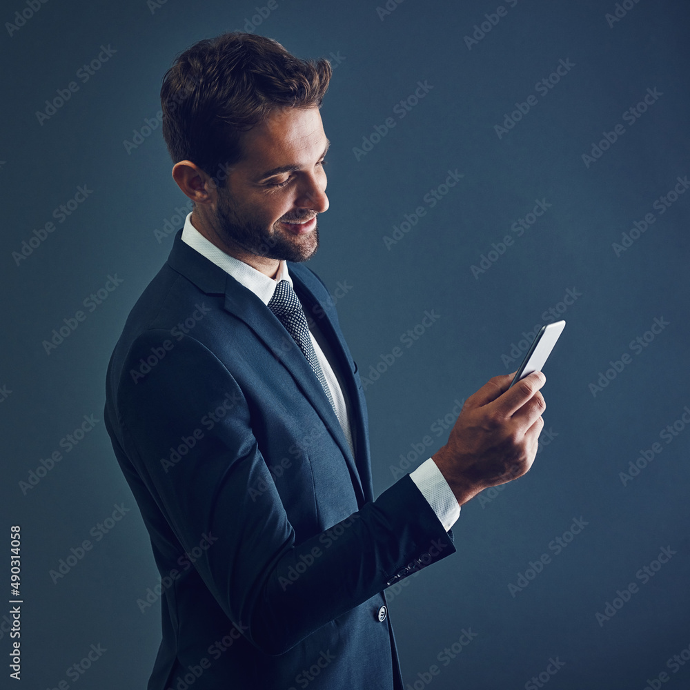 Make the connection thatll move you forward. Studio shot of a handsome young businessman using a cellphone against a dark background. Make the connection thatll move you forward. Studio shot of a handsome young businessman using a cellphone against a dark background.