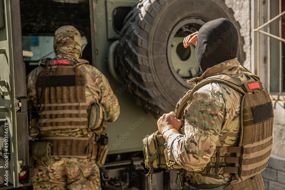 Fototapeta premium Military operations in Ukraine. A soldier with machine guns near an armored personnel carrier. The military repulse the attack of the invaders, hold the defense, capture the terrorists.