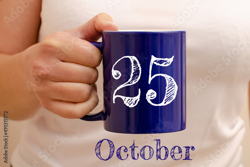 The inscription on the blue cup 25 october. Cup in female hand, business concept