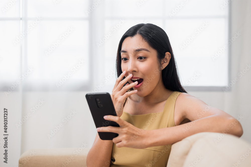 Asian woman using smartphone. Chatting video conference online sitting sofa in living room at home. Business Woman Shopping online store. Relax time at home Asian woman using smartphone. Chatting video conference online sitting sofa in living room at home. Business Woman Shopping online store. Relax time at home