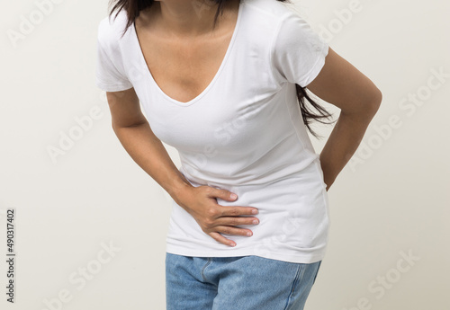 A woman had a stomach ache and gastritis. She put her hand on her stomach and squeezed it to relax and soothe. She is 25 years old and has menstrual cramps. Shot on isolated white background.