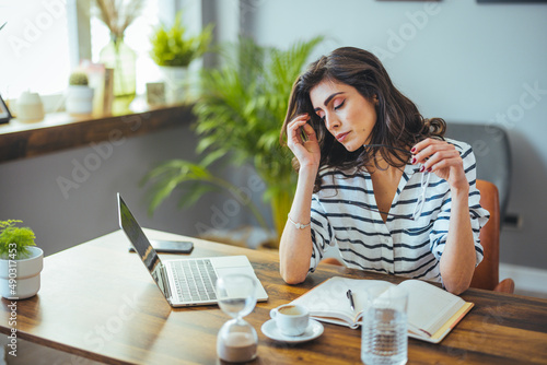 Deadline Stress. Overworked  Female Entrepreneur Massaging Nosebridge At Workplace In Office, Exhausted After Using Laptop. Woman headache stressed. photo