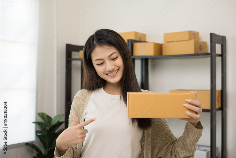 Beautiful young asian entrepreneur standing pose. Female small Business owner with box working at home. Startup freelance people with many parcel on background. Beautiful young asian entrepreneur standing pose. Female small Business owner with box working at home. Startup freelance people with many parcel on background.