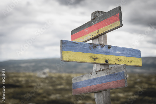 germany ukraine russia flag on wooden signpost outdoors in nature. Conflict in ukraine concept.