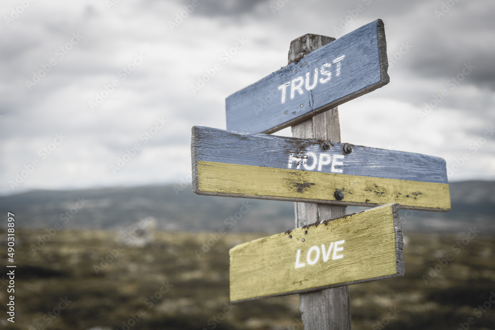 trust hope love text quote on wooden signpost outdoors, written on the ukranian flag.