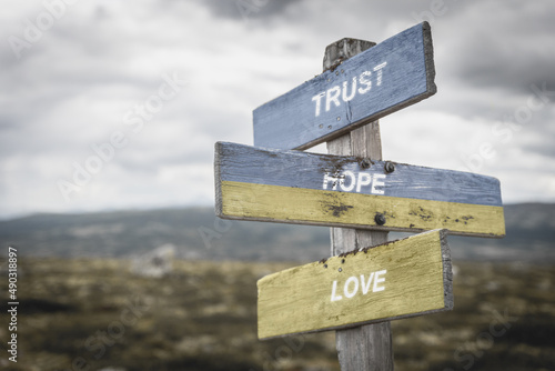 trust hope love text quote on wooden signpost outdoors, written on the ukranian flag.