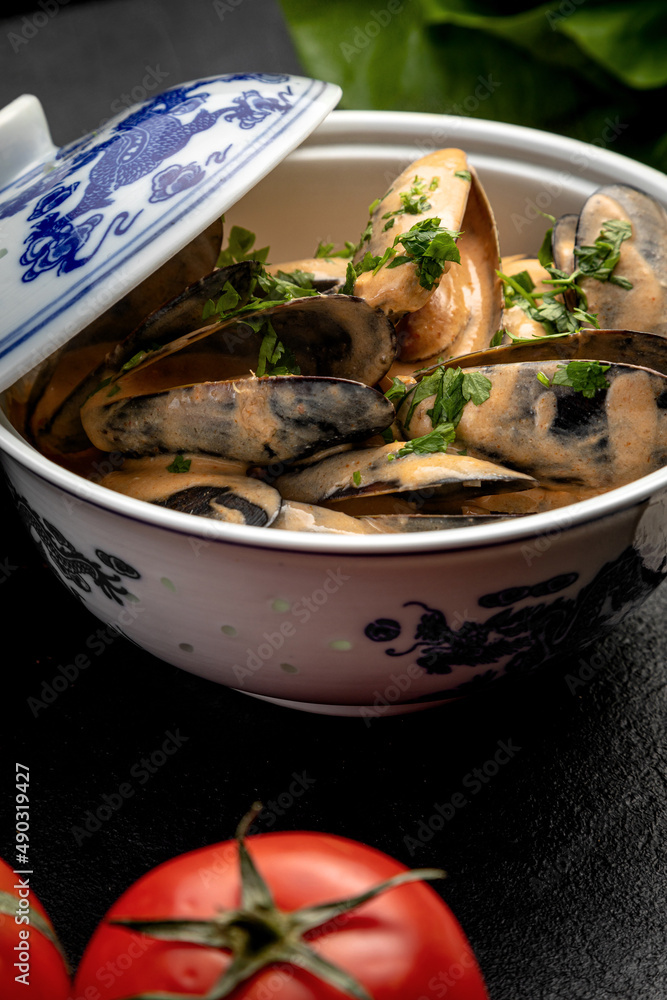 mussels in sauce in a ceramic dish on a dark decorated background