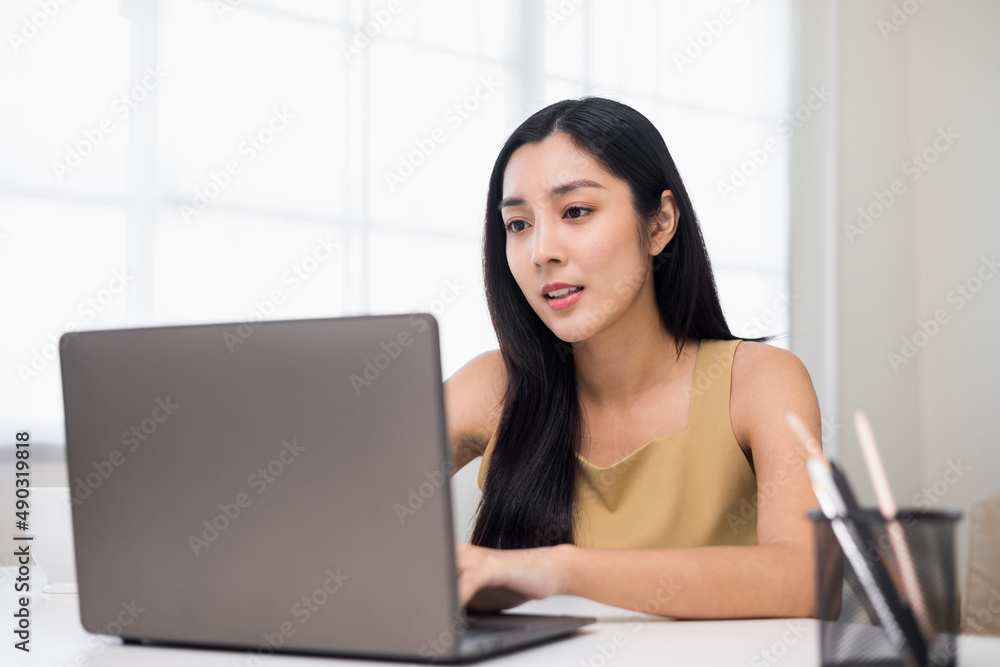 Asian Woman looking at screen Meeting on social media. Beautiful asian woman using laptop chatting video conference online sitting in living room at home. Work from home. Asian Woman looking at screen Meeting on social media. Beautiful asian woman using laptop chatting video conference online sitting in living room at home. Work from home.