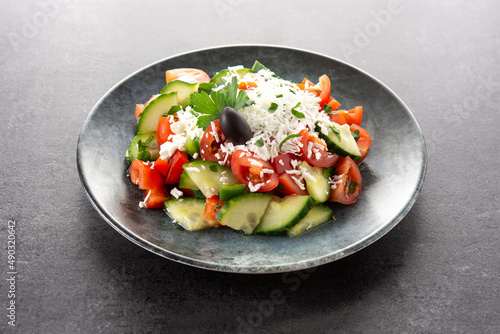 Traditional Bulgarian shopska salad with tomato,cucumber and bulgarian sirene cheese on black background