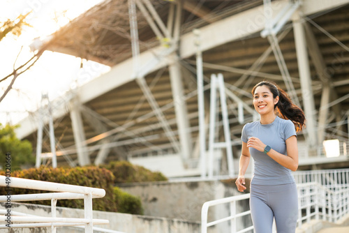 Attractive beautiful woman wearing sportswear running at sport stadium. Fit woman jogging outdoor. Workout exercise in the morning. Healthy and active lifestyle concept. © Chanakon