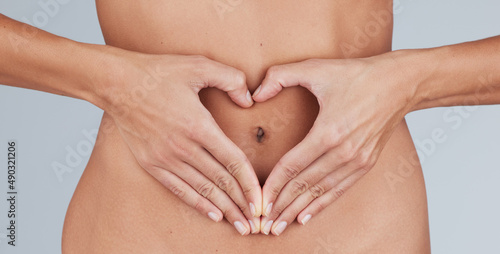 Wallpaper Mural Giving some love to my gut. Cropped shot of an unrecognizable woman standing alone in the studio and making a heart-shaped gesture over her tummy. Torontodigital.ca