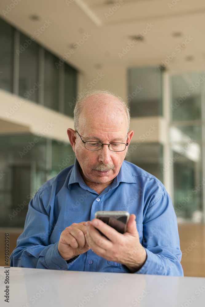 Portrait of senior businessman sitting at office and using phone Portrait of senior businessman sitting at office and using phone