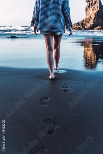 lonely woman walks along a black beach