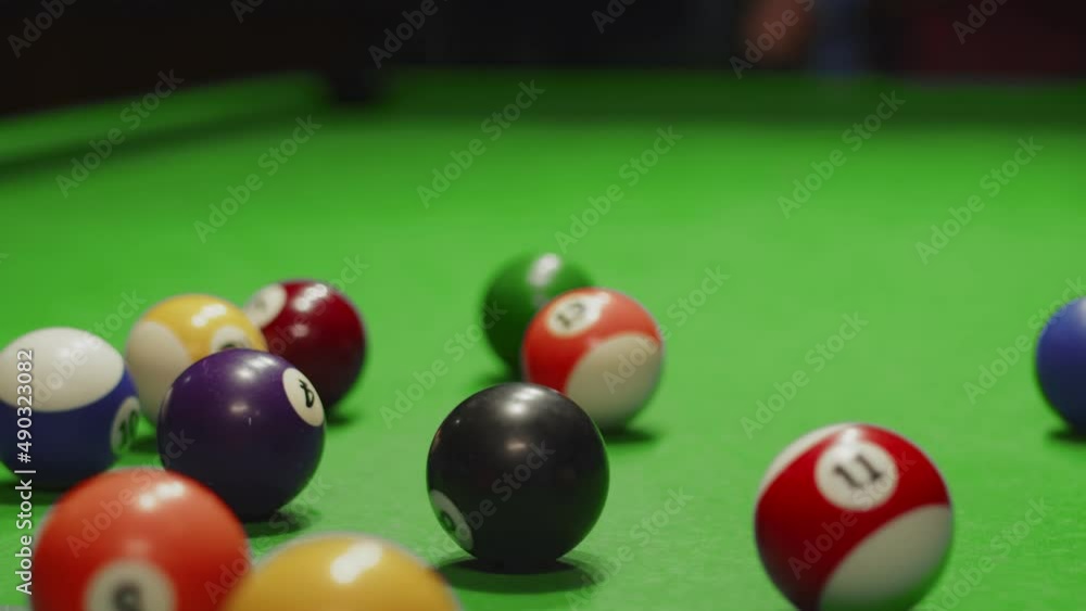 Closeup of billiard balls on table assembled in triangle, formation breaks white ball that was hit with cue. Man is playing billiards. Entertainment concept Closeup of billiard balls on table assembled in triangle, formation breaks white ball that was hit with cue. Man is playing billiards. Entertainment concept