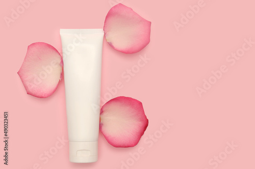 White container for cosmetic cream. Rose petals.