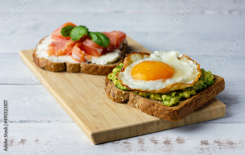 Two sandwiches with smoked salmon, cream cheese, avocado and fried egg. Concept for healthy nutrition.