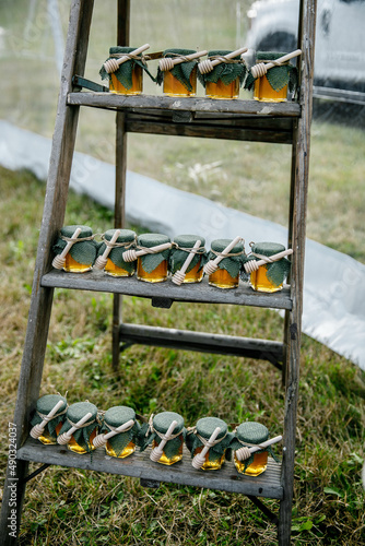 Fotografía Dark wooden stand with jars of honey Isolated Honey in the glass bottles for a w
