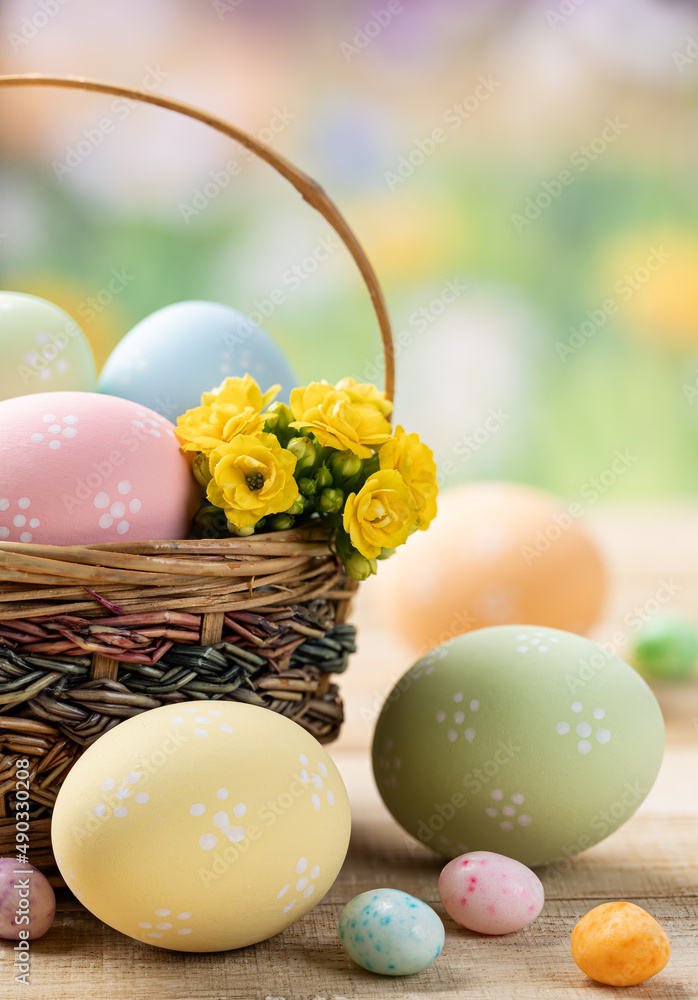 Obraz premium Colored easter eggs with basket and flowers