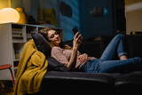 woman relaxing on a sofa and using smartphone at home
