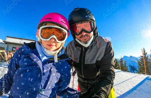 Family enjoying winter vacations taking selfie in skiing gear.
