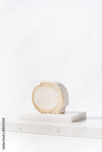 Trozo de queso de cabra cremoso sobre mármol y fondo claro