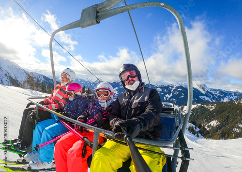 Family riding ski lift cable car on winter vacation skiing.