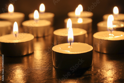 pointLots of candles on a wooden tablefocusspot specifically in on a black background.