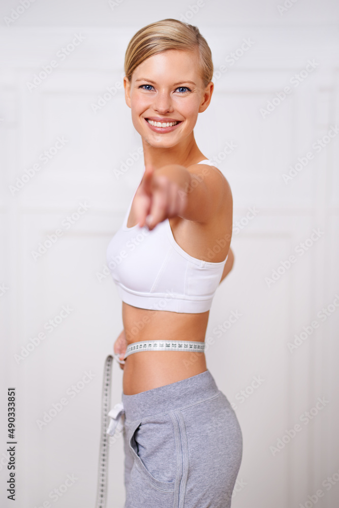 Ive reached my goal weight and so can you. A portrait of a beautiful young woman measuring her waist and pointing.