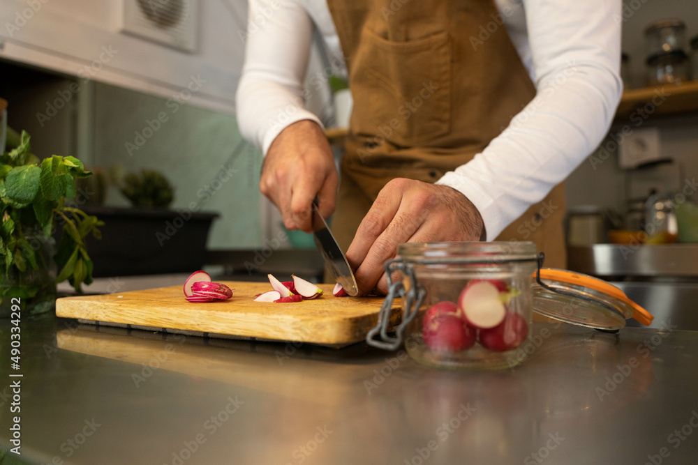 Hands of the cook cutting radish in his food truck. Copy space. Hands of the cook cutting radish in his food truck. Copy space.