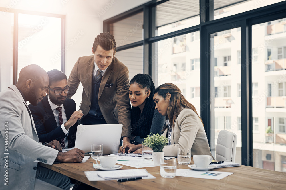 Work together, get more done together. Shot of a group of young businesspeople using a laptop together during a meeting in a modern office.