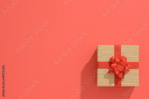 One grey gift box with Red sparkle ribbon and bow on red table background. Minimal festive gift background. Top view. Flat lay.	